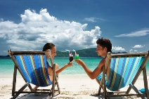 stock-photo-couple-on-a-tropical-beach-in-chaise-lounge-51737842